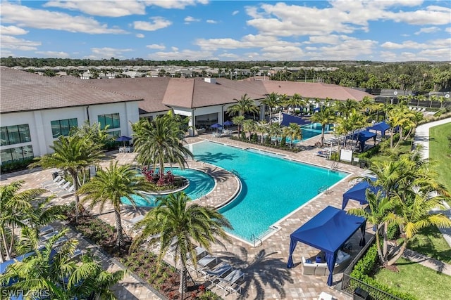 community pool with a patio area, fence, and a residential view