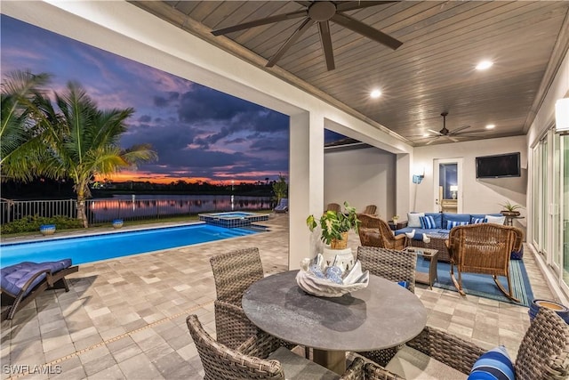 view of swimming pool with a fenced backyard, outdoor lounge area, a water view, a ceiling fan, and a patio area