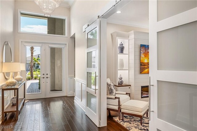 entryway with a high ceiling, dark hardwood / wood-style floors, a chandelier, crown molding, and french doors