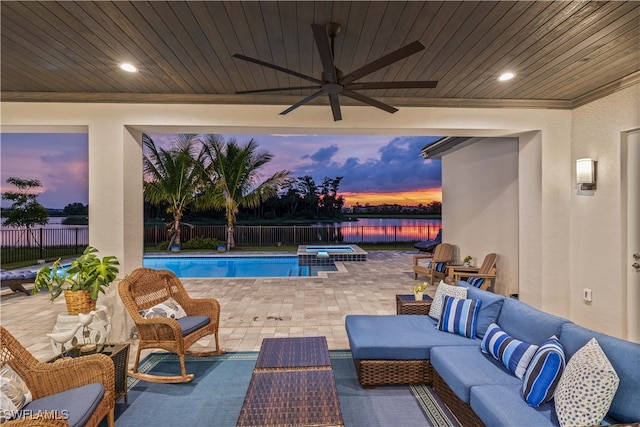 pool at dusk with ceiling fan, an outdoor living space, and a patio area