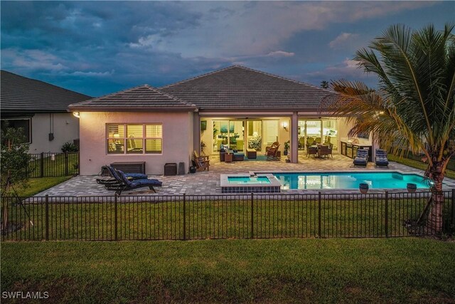 pool at dusk featuring a patio area, a lawn, and an in ground hot tub