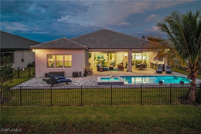 back of house featuring a yard, stucco siding, a pool with connected hot tub, a patio area, and fence