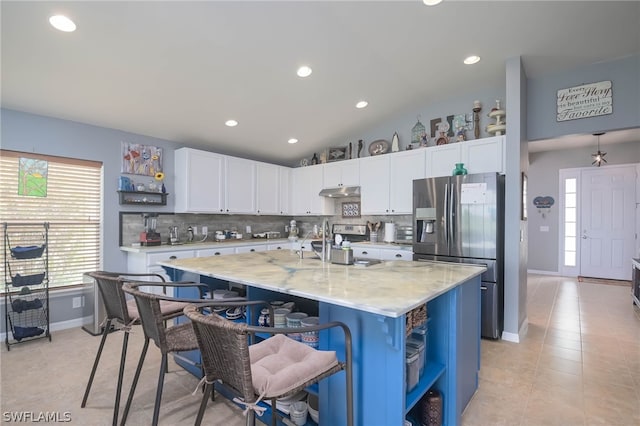 kitchen featuring a center island with sink, lofted ceiling, appliances with stainless steel finishes, and white cabinetry