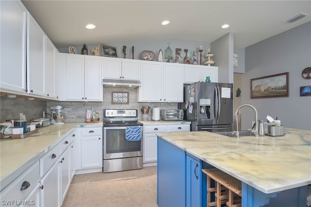 kitchen with white cabinetry, light stone counters, stainless steel appliances, and backsplash