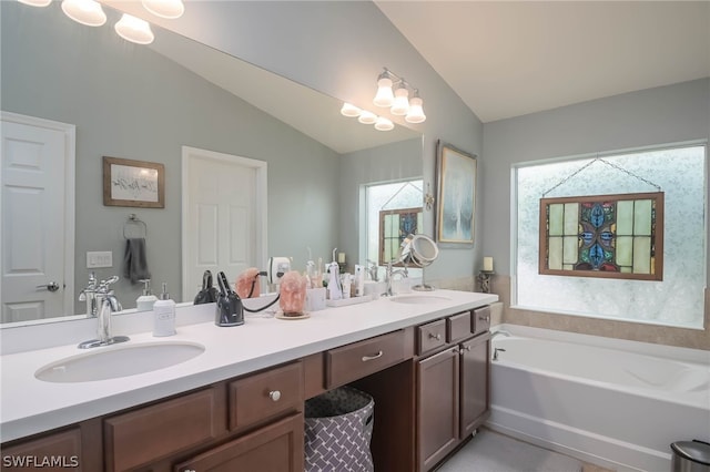 bathroom with vanity, a tub to relax in, and lofted ceiling