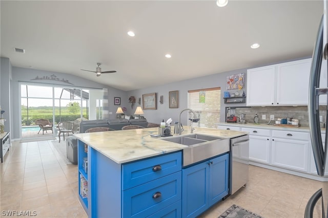 kitchen featuring blue cabinets, vaulted ceiling, stainless steel appliances, and white cabinetry