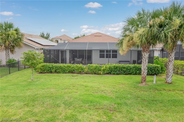 back of property with a yard and glass enclosure