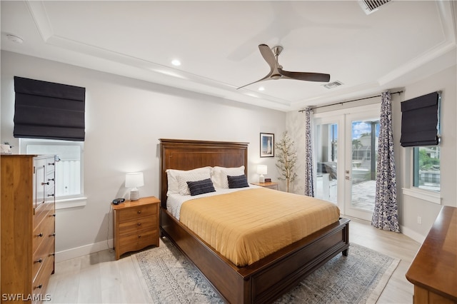 bedroom with hardwood / wood-style floors, ceiling fan, a tray ceiling, and access to outside