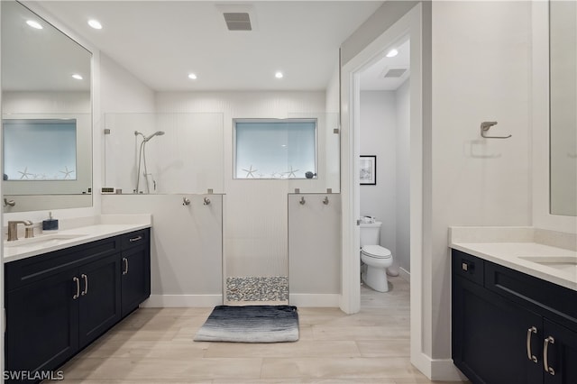 bathroom featuring a tile shower, vanity, and toilet