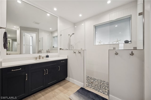 bathroom with a tile shower, hardwood / wood-style flooring, and vanity