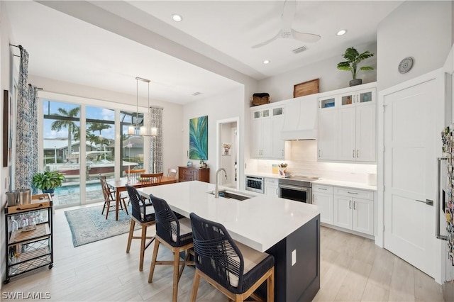1641 Orleans Ct, Marco Island, FL 34145 - kitchen featuring a sink, ceiling fan, premium range hood, a breakfast bar, and tasteful backsplash