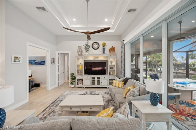 living room featuring ceiling fan, a tray ceiling, and light hardwood / wood-style flooring