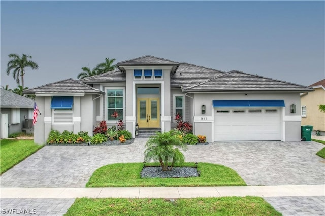 1641 Orleans Ct, Marco Island, FL 34145 - prairie-style house featuring french doors, stucco siding, a garage, and decorative driveway