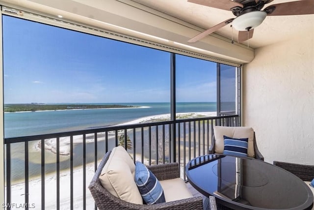 balcony featuring a beach view, ceiling fan, and a water view