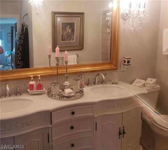 bathroom with a notable chandelier, toilet, and double sink vanity