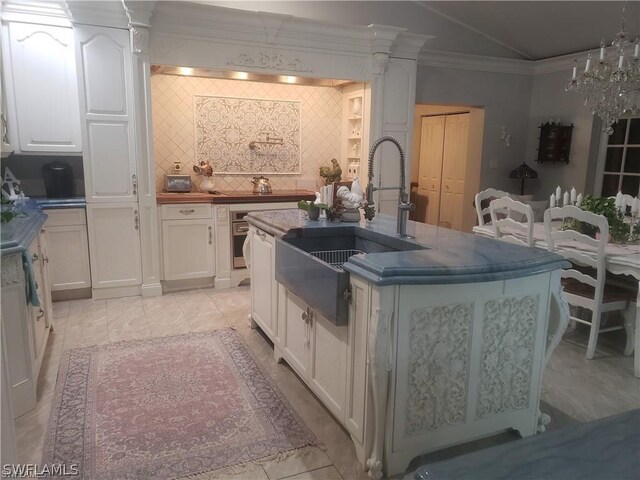 kitchen featuring sink, white cabinetry, a kitchen island with sink, and ornamental molding