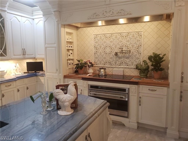 kitchen with white cabinets, black electric cooktop, backsplash, stainless steel oven, and light tile floors