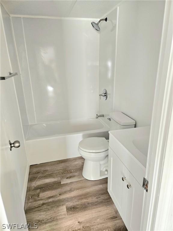 full bathroom with shower / bathing tub combination, vanity, toilet, and hardwood / wood-style floors