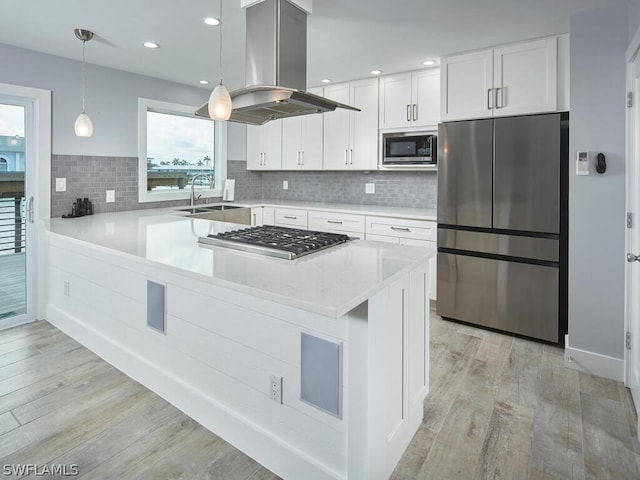 kitchen with sink, white cabinetry, island range hood, pendant lighting, and stainless steel appliances