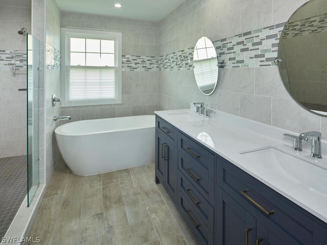 bathroom with tile walls, vanity, hardwood / wood-style floors, and plus walk in shower