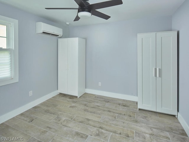 unfurnished bedroom featuring ceiling fan, a wall unit AC, and light hardwood / wood-style flooring