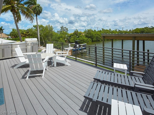 wooden terrace featuring a water view, an outdoor kitchen, and area for grilling