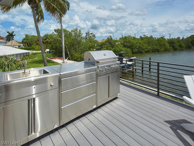 wooden terrace featuring exterior kitchen, a water view, and sink