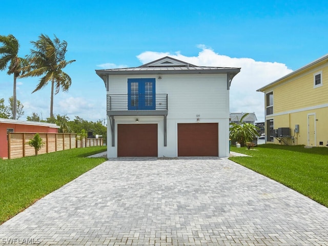 view of property featuring french doors, a balcony, a garage, and a front yard