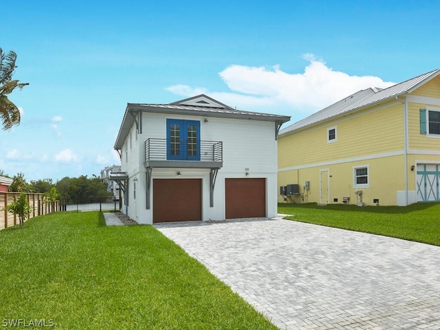 back of property featuring a garage, a lawn, and a balcony