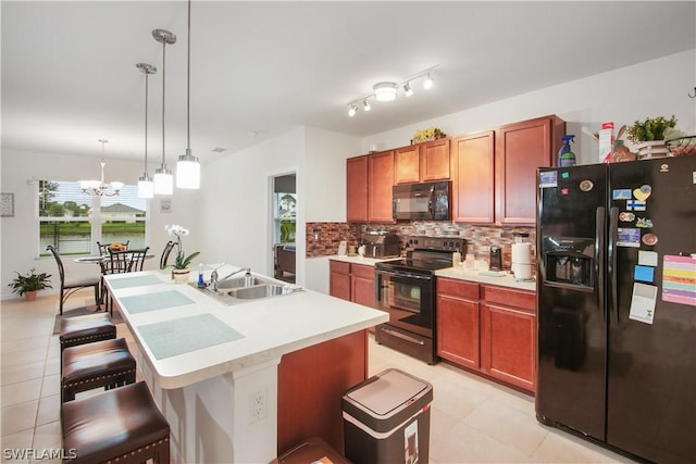 kitchen featuring pendant lighting, black appliances, a kitchen breakfast bar, sink, and a notable chandelier