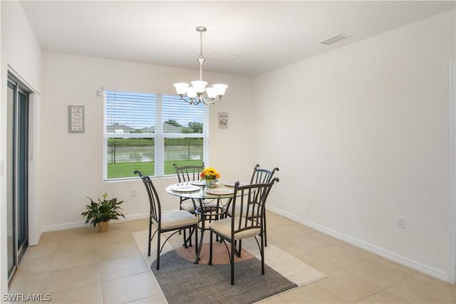 dining room with a notable chandelier, a water view, and light tile patterned floors