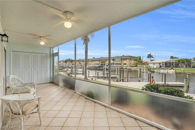 unfurnished sunroom with ceiling fan and a water view