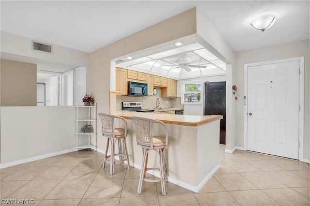 kitchen featuring light brown cabinets, ceiling fan, stainless steel electric range oven, a kitchen bar, and kitchen peninsula