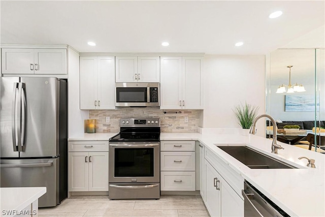 kitchen featuring white cabinetry, appliances with stainless steel finishes, a notable chandelier, decorative light fixtures, and sink