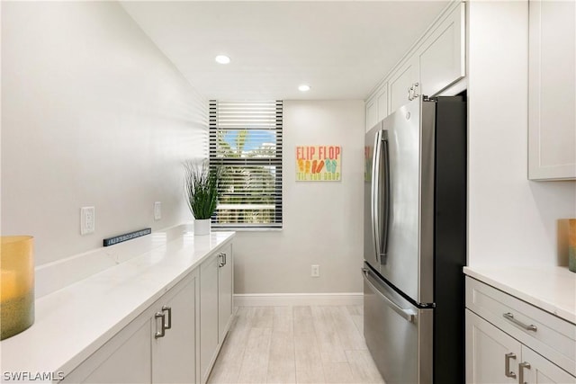 kitchen featuring white cabinets, stainless steel fridge, and light wood-type flooring