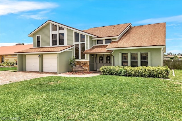 view of front facade with a shingled roof, a front yard, decorative driveway, and stucco siding