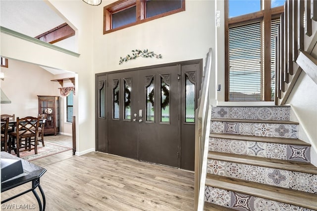 foyer entrance featuring baseboards, stairway, a towering ceiling, and wood finished floors