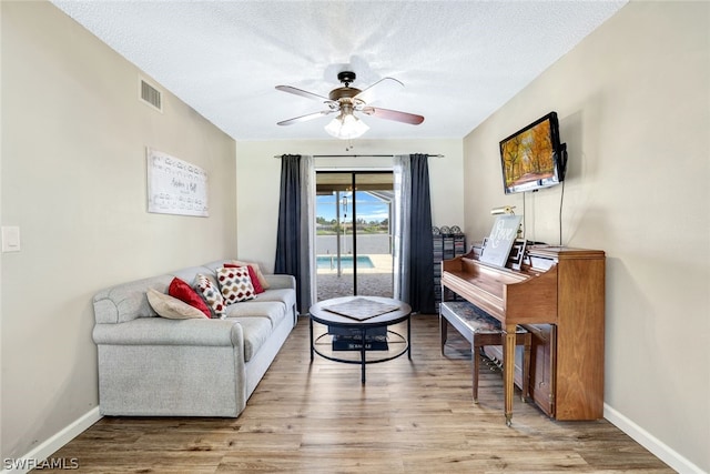 interior space featuring a ceiling fan, visible vents, baseboards, and wood finished floors