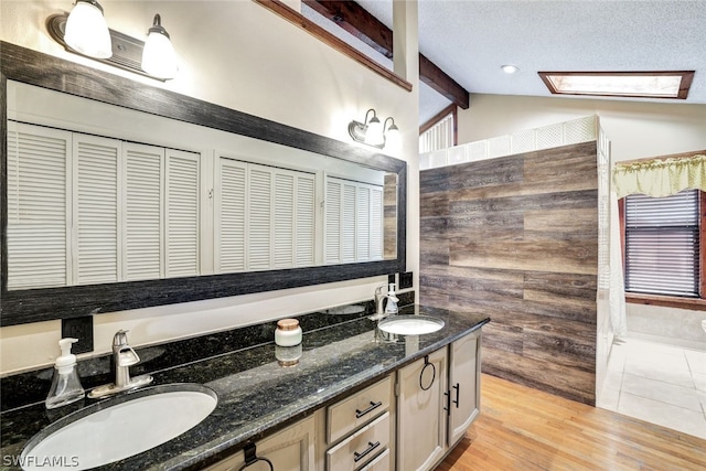 bathroom featuring lofted ceiling with beams, double vanity, wood finished floors, and a sink