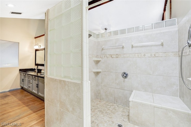 bathroom with vanity, wood finished floors, walk in shower, and visible vents