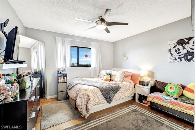 bedroom with ceiling fan, a textured ceiling, and wood finished floors