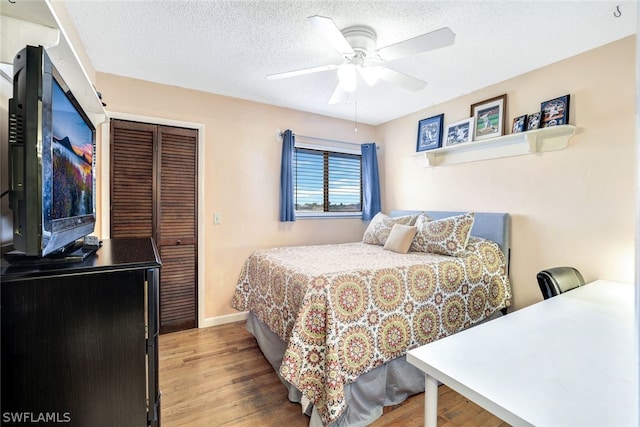 bedroom featuring a closet, a textured ceiling, baseboards, and wood finished floors