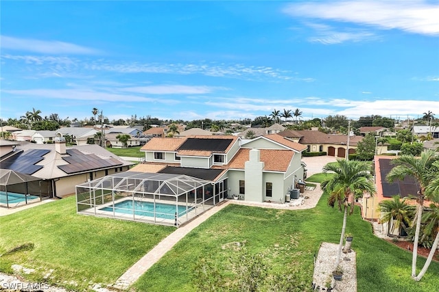 rear view of house featuring an outdoor pool, a residential view, a lanai, and a lawn