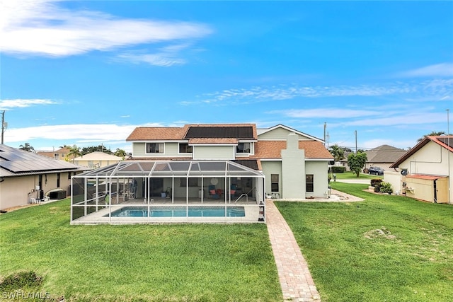 back of house with an outdoor pool, glass enclosure, a yard, and a patio