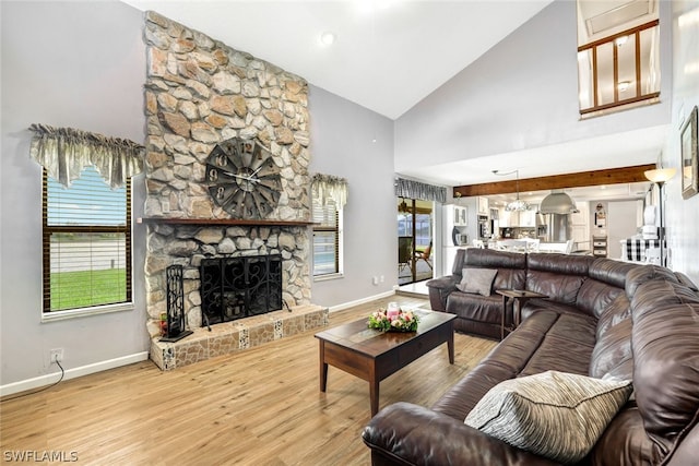 living room with high vaulted ceiling, a stone fireplace, baseboards, and wood finished floors