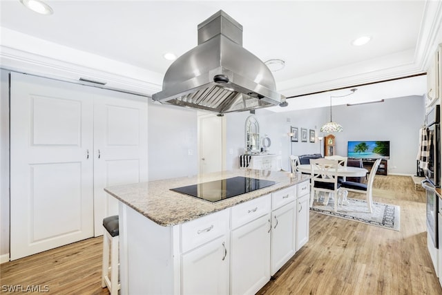 kitchen featuring island range hood, white cabinets, light wood-style flooring, a kitchen island, and black electric cooktop