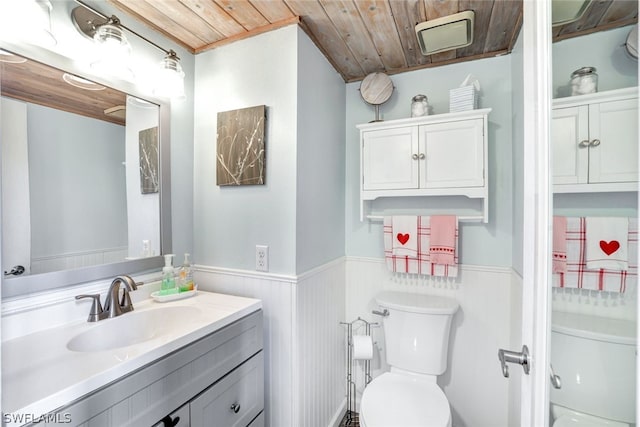 bathroom with toilet, wooden ceiling, a wainscoted wall, and vanity