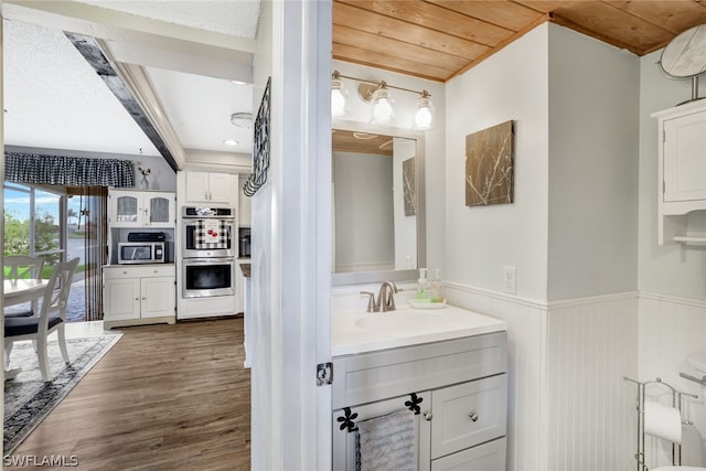 bathroom featuring vanity, wainscoting, wood finished floors, and wood ceiling