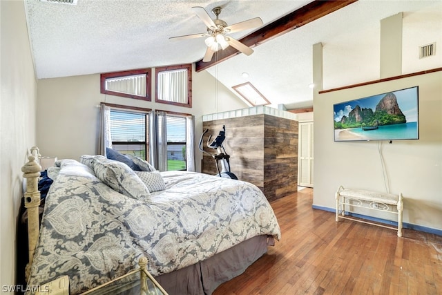 bedroom with lofted ceiling with beams, a textured ceiling, visible vents, baseboards, and wood-type flooring