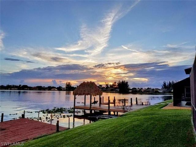 view of dock featuring a lawn and a water view